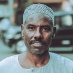 man in white crew neck shirt wearing gray and white checkered bandana